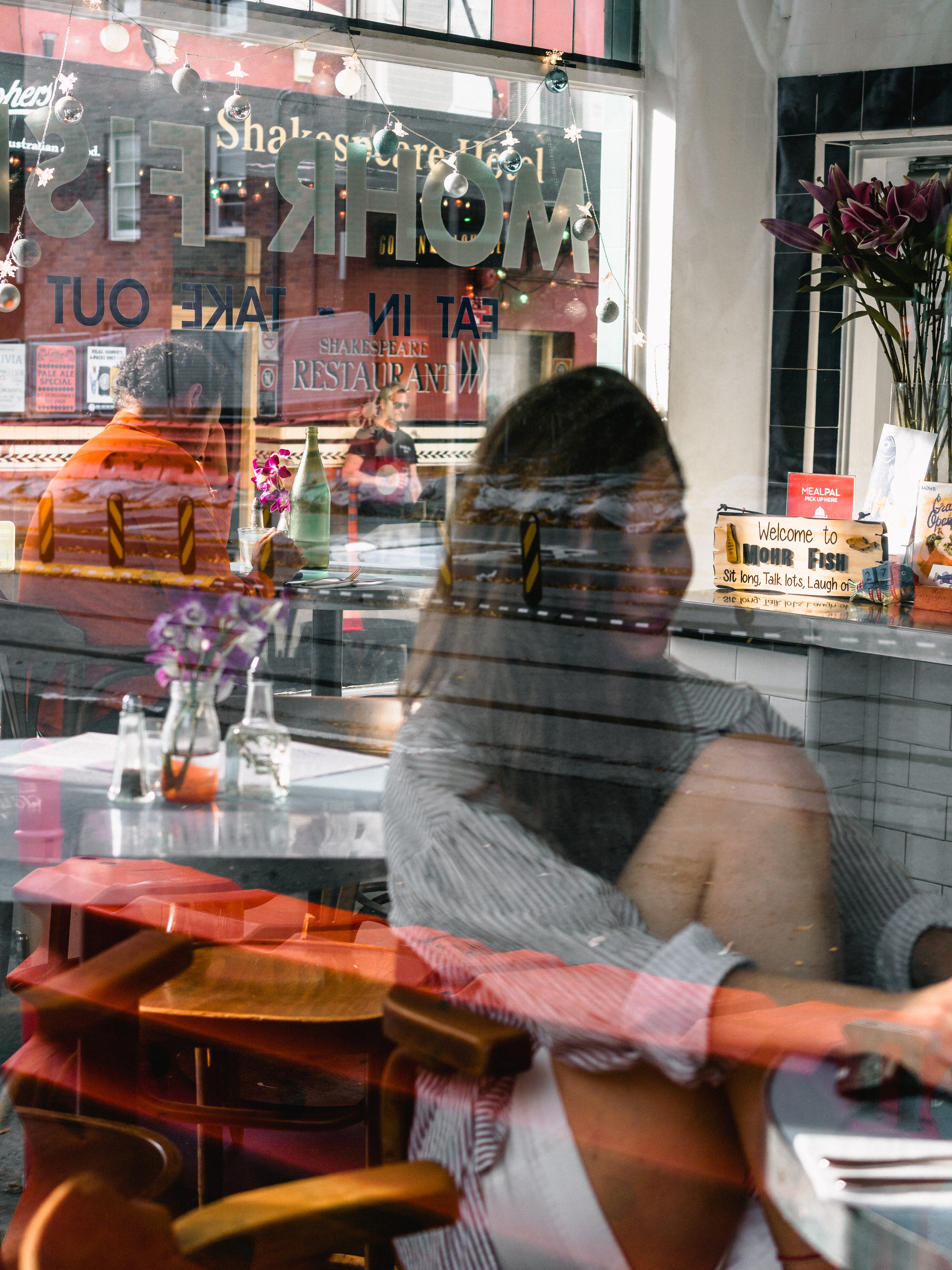 Looking inside cafe with woman looking at computer and man in back looking at phone_pexels-matt-hardy-2022